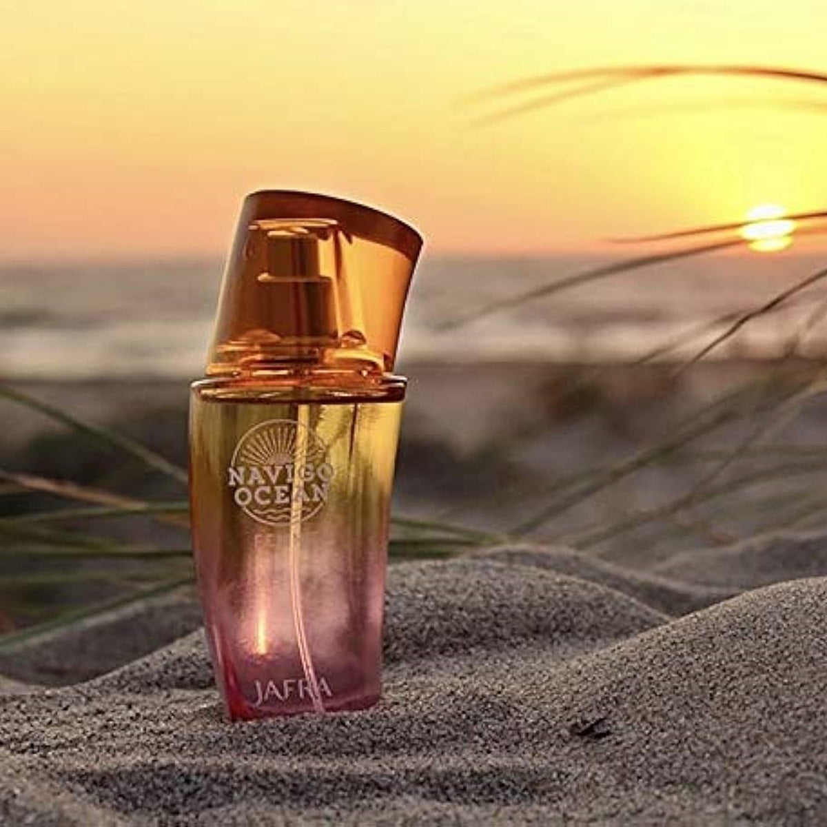 Perfume bottle on sand with sunset in the background