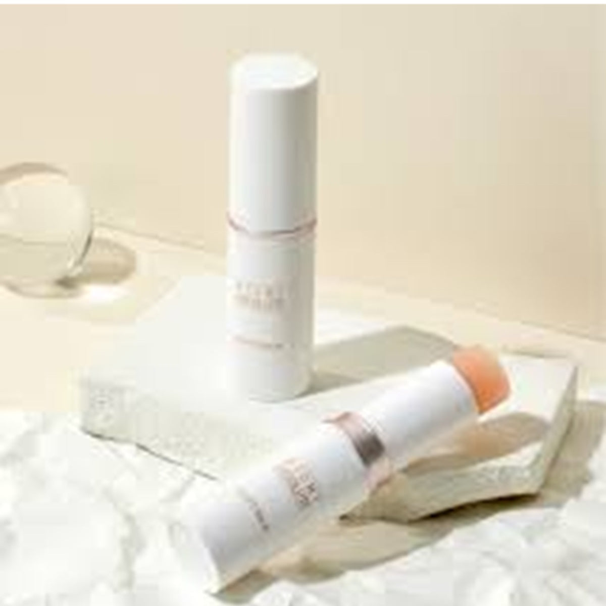 Two skincare products on a white surface with a neutral background