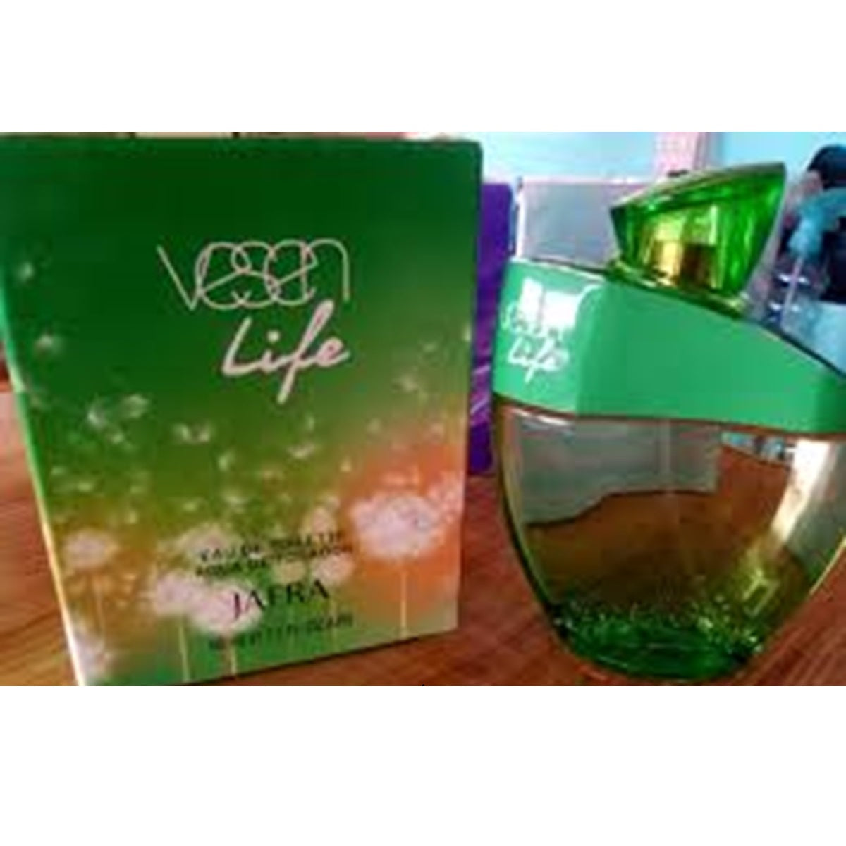 Green perfume bottle and packaging with 'Vegan Life' branding on a wooden surface.